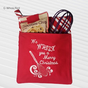 May include: Red fabric kitchen pot holder with white embroidery that says "We Whisk you a Merry Christmas" and a white embroidered whisk. The pot holder has a pocket with a package of chocolate chip cookie mix and a purple whisk inside.