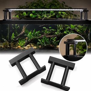 May include: Two black aquarium light stand risers featuring a rectangular base and top connected by two vertical cylindrical pillars. These components are designed to elevate lighting fixtures above a fish tank, as shown in the circular inset.