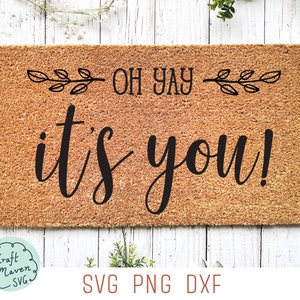 May include: A rectangular doormat made of natural coir fiber. The mat features the phrase "OH YAY it's you!" in black script, with decorative leaf accents. The bottom of the mat displays "SVG PNG DXF".