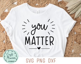 以下が含まれることがあります： 白いTシャツに黒い文字で「you matter」と書かれており、その下に小さなハートがあります。テキストは放射状の線で囲まれています。