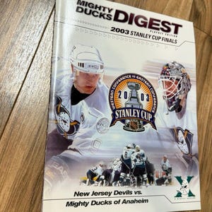 May include: A Mighty Ducks Digest magazine from the 2003 Stanley Cup Finals. The cover features hockey players in action, the Stanley Cup logo, and the text "New Jersey Devils vs. Mighty Ducks of Anaheim."