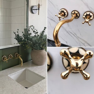 Pu&ograve; includere: Rubinetto da bagno dorato con una maniglia a motivo bianco e nero. Il rubinetto &egrave; montato su una parete in marmo bianco.
