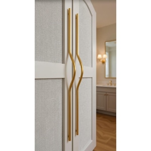 May include: Close-up of a white cabinet door with a woven texture and gold-colored, curved handles. The cabinet door is part of a larger piece of furniture, possibly a closet or a bathroom vanity.