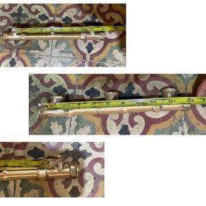 May include: A brass door handle, approximately 10 inches long, is shown with a yellow measuring tape. The handle has a bamboo-like design with three circular knobs. The background is a patterned tile surface.
