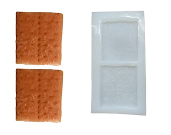 May include: Two brown rectangular cookies with a textured surface and a white silicone mold with two rectangular cavities.