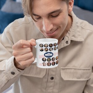May include: White ceramic mug featuring portraits of U.S. presidents in circular frames. The mug has a design of the White House and the text "THE WHITE HOUSE WASHINGTON". The mug is held by a person wearing a beige shirt.