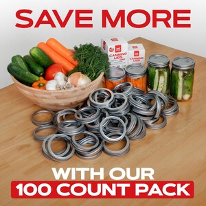 K&ouml;nnte beinhalten: Ein gro&szlig;er Stapel von 100 silbernen Einmachdeckeln, mit zwei Schachteln Einmachdeckeln im Hintergrund. Die Schachteln sind rot und wei&szlig; und tragen die Aufschrift "Canning Lids". Im Hintergrund befinden sich auch Gl&auml;ser mit Gurken und Karotten.