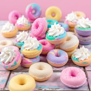 May include: A variety of colorful and decorated donuts with white frosting and sprinkles. Some donuts have a swirl design, while others have a simple glaze. The donuts are arranged on a white wooden surface.