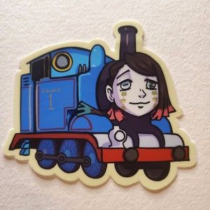 May include: A sticker depicting a blue cartoon train with the number 1 and the word "tower" on the side. A cartoon character with dark hair and a pale complexion is superimposed on the train.