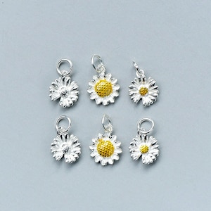 May include: Six silver daisy charms with yellow centers. The charms are designed to be used for jewelry making.