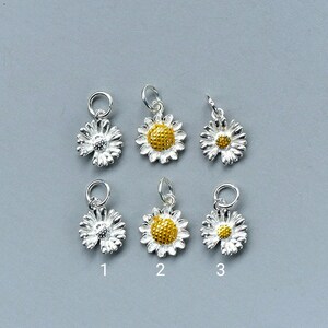 May include: Six silver daisy charms with yellow centers. Three charms have a solid yellow center and three charms have a silver center with a yellow center.