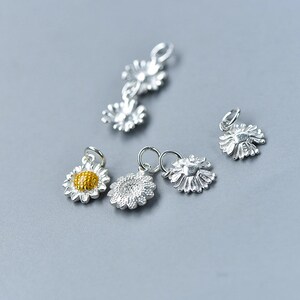 May include: Five silver daisy charms with a yellow center. The charms are perfect for adding a touch of whimsy to jewelry projects.