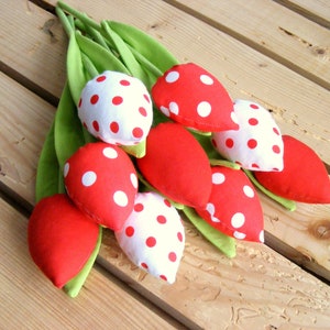 May include: A bouquet of red and white fabric tulips with white polka dots. The tulips are arranged on a wooden surface.
