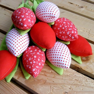 Può includere: Un mazzo di tulipani di stoffa rossi e bianchi con steli verdi. I tulipani sono realizzati con tessuti a motivi diversi, tra cui pois e stampe floreali.