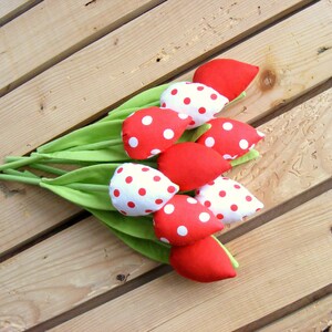 May include: A bouquet of red and white fabric tulips with white polka dots on a wooden surface.