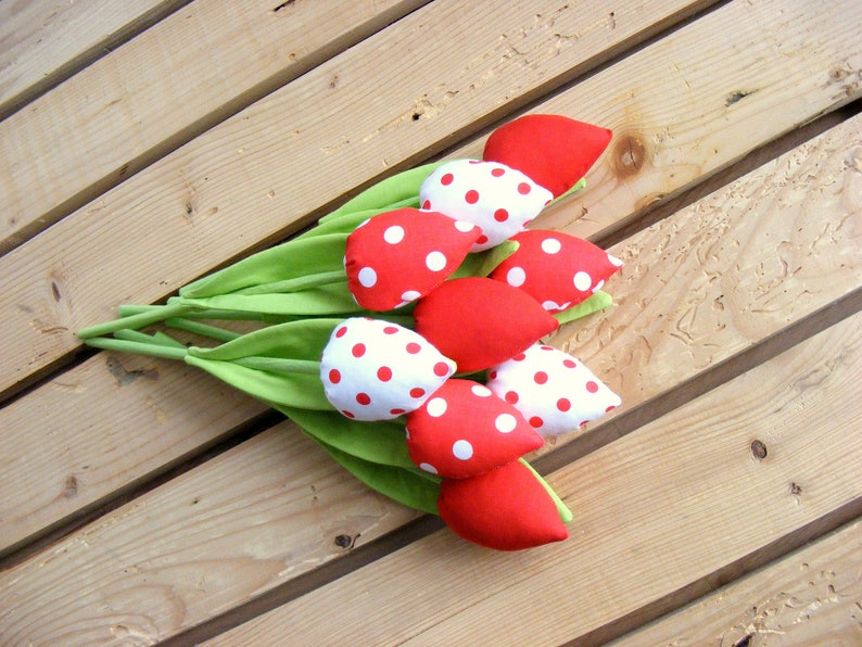 May include: A bouquet of red and white fabric tulips with white polka dots on a wooden surface.