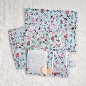 Puede incluir: Tres bolsas con cremallera azules y blancas con un patrón de vaca y flores. Las bolsas están forradas con plástico transparente y tienen un cierre de cremallera. Las bolsas son perfectas para organizar artículos pequeños.