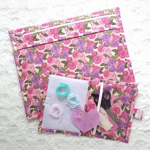 Peut inclure: Une trousse de couture en tissu floral rose avec plusieurs poches et compartiments. La trousse comprend une paire de ciseaux, du fil et un coussin à aiguilles en forme de cœur.