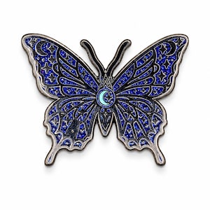 Puede incluir: Un broche de esmalte con forma de mariposa que presenta un fondo de purpurina azul oscuro con contornos de metal negro. Las alas est&aacute;n decoradas con patrones celestiales que incluyen estrellas, lunas crecientes y un icono central.