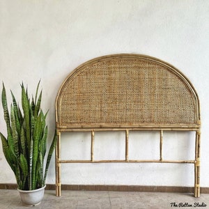 May include: A natural woven rattan headboard with a rounded top and a simple frame. The headboard is made of light brown bamboo and has a woven pattern.