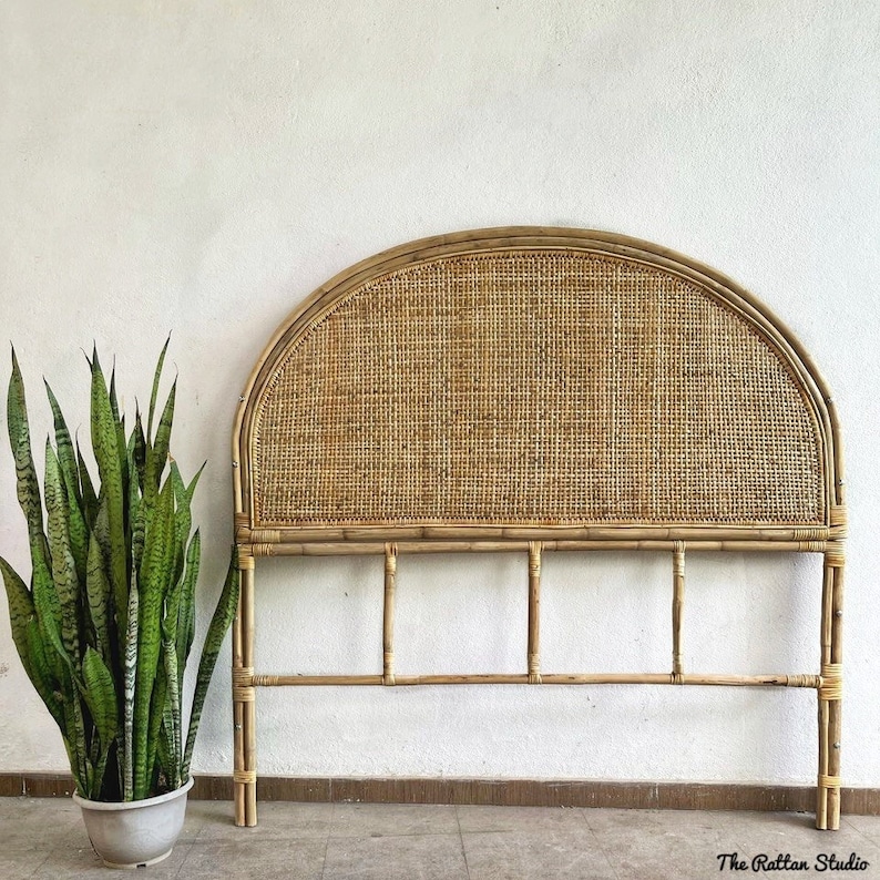 May include: A natural woven rattan headboard with a rounded top and a simple frame. The headboard is made of light brown bamboo and has a woven pattern.