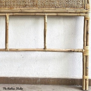 May include: A natural woven rattan headboard with a rectangular shape and a woven design. The headboard is made of natural brown bamboo and has a simple, elegant design.
