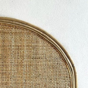 May include: A half-round headboard made of woven rattan with a natural brown color.