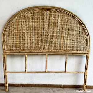 May include: A natural woven rattan headboard with a curved top and a rectangular frame. The headboard is made of light brown bamboo and has a woven pattern.