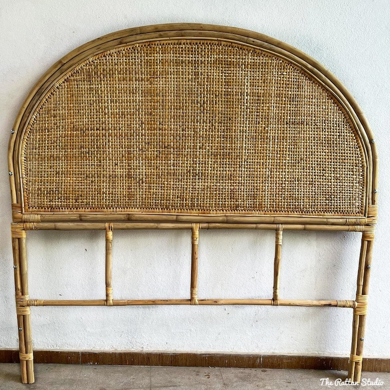 May include: A natural woven rattan headboard with a curved top and a rectangular frame. The headboard is made of light brown bamboo and has a woven pattern.