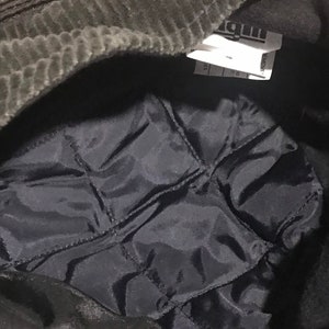 May include: A black corduroy hat with a black quilted lining. The hat has a label that says "REMOVE" and "MADE IN CHINA".