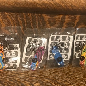 May include: Four individually packaged finger skateboards with colorful designs. Each package features the text "Skate Escape" and a 3+ age recommendation.