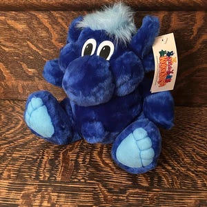 May include: Blue plush toy with a blue and white face and large blue feet. The toy has a tag that says "Kookla's Kolor Kids".