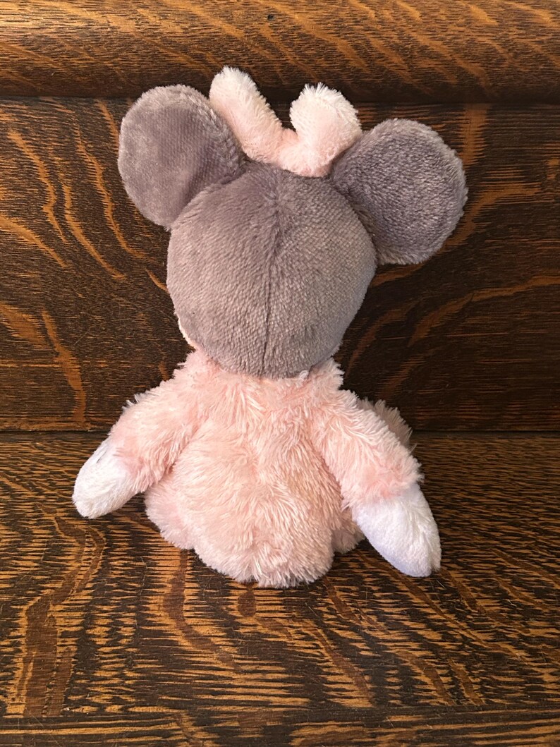 May include: A plush toy mouse with gray ears and head, a pink crown, and a pink body. The mouse has white paws and is made of soft, fuzzy material. The toy is designed for children.
