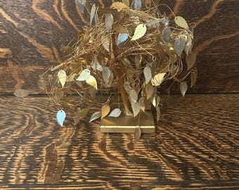 May include: A gold wire tree sculpture with gold leaf accents. The tree is on a square base and has a whimsical, organic shape.