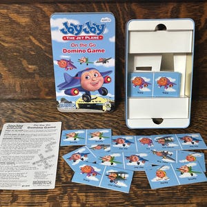 May include: A Jay Jay the Jet Plane On the Go Domino Game set. The game includes a blue tin with the game title, a white box, domino tiles, and instructions. The domino tiles feature cartoon airplanes.