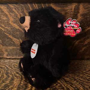 Könnte beinhalten: Schwarzer Plüsch-Bär mit einem roten Etikett, auf dem "Bear Buddies" steht. Das Etikett sagt auch "My name is Jonathan, was born on: August 20th, I am a: Black Bear, 12M+"