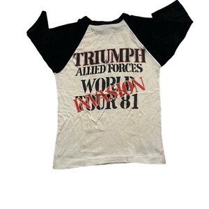 May include: A white t-shirt with black sleeves. The back of the shirt has the text "Triumph Allied Forces World Invasion Tour 81" printed on it.