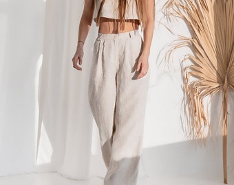 Pode incluir: Uma mulher vestindo um top curto de linho bege e calças largas combinando. O visual é simples e elegante, perfeito para um dia de verão.