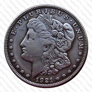 May include: A silver US dollar coin with the inscription "E PLURIBUS UNUM" and "LIBERTY" on the obverse. The coin features a profile of a woman with flowing hair and a wreath on her head. The date "1921" is inscribed on the bottom of the coin.