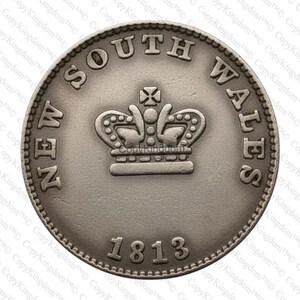 May include: A silver coin from New South Wales, dated 1813, features the text "NEW SOUTH WALES" around the edge. A detailed crown is in the center. The coin has a detailed, textured surface.