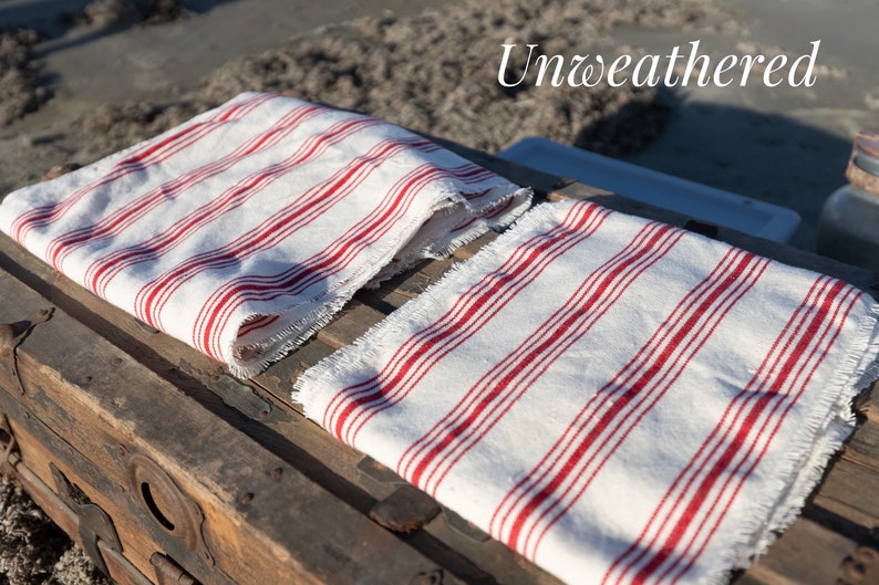 May include: Two white and red striped fabric napkins with frayed edges. The napkins are folded and placed on top of a wooden chest.