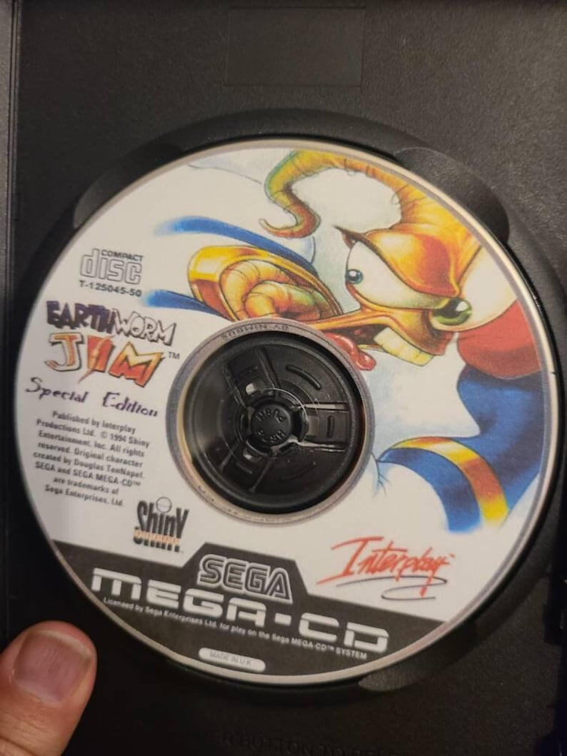May include: Earthworm Jim Special Edition Sega Mega-CD game disc. The disc features a cartoon image of Earthworm Jim. The disc is in a black case. The disc has the Sega Mega-CD logo and the Interplay logo.