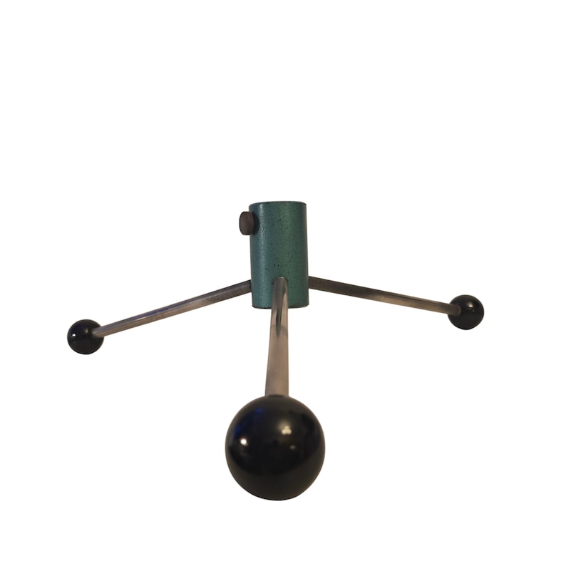 May include: A teal metal Christmas tree stand with three silver arms extending outwards, each ending in a black sphere. The central support is cylindrical with a screw. The stand is designed to hold a Christmas tree.