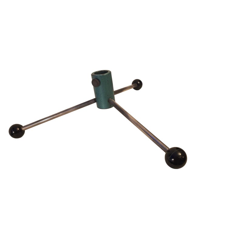 May include: A green metal Christmas tree stand with three silver legs. Each leg has a black ball at the end. The stand has a cylindrical shape with a hole at the top for the tree trunk.