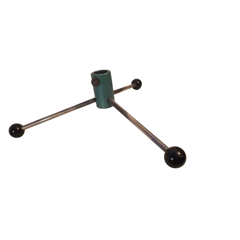 May include: A green metal Christmas tree stand with three silver legs. Each leg has a black ball at the end. The stand has a cylindrical shape with a hole at the top for the tree trunk.