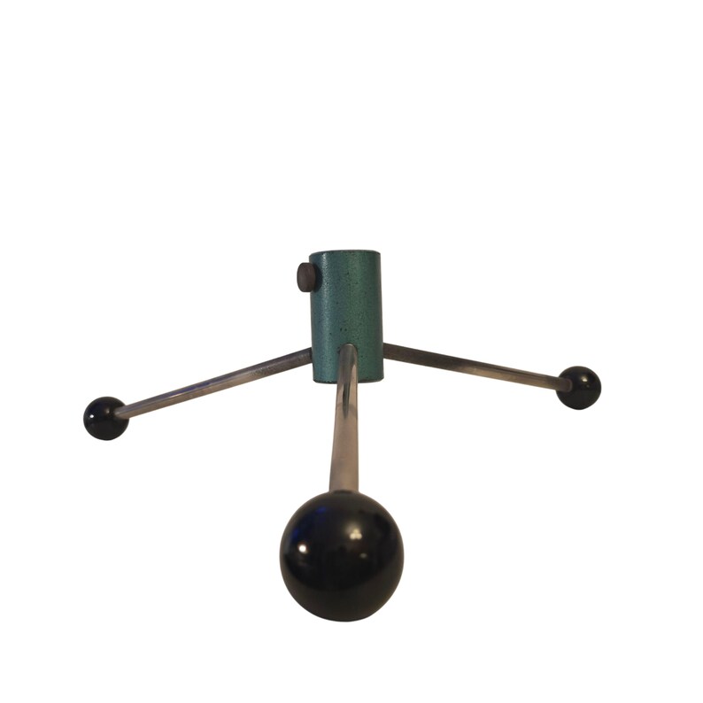 May include: A vintage Christmas tree stand with a teal green cylindrical base and three silver arms extending outwards. Each arm ends with a black sphere. A black sphere is also at the bottom of the stand.
