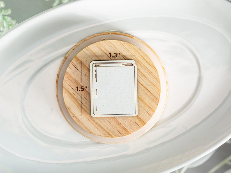 May include: A wooden coaster with a white rectangle in the center. The rectangle is 1.3 inches wide and 1.5 inches tall. The coaster is a great way to protect your furniture from hot drinks.