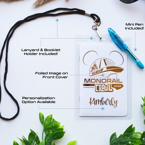 May include: White card with a gold foil image of a monorail and the text "Monorail Crawl 2022" and the name "Kimberly". The card is attached to a black lanyard and comes with a mini pen.