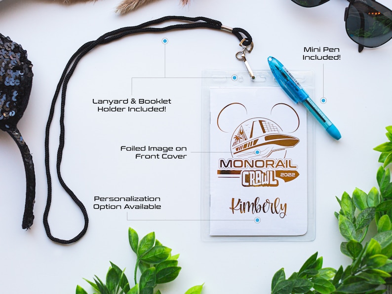 May include: White card with a gold foil image of a monorail and the text "Monorail Crawl 2022" and the name "Kimberly". The card is attached to a black lanyard and comes with a mini pen.