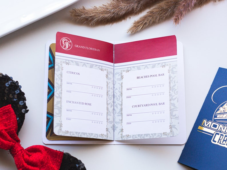 May include: A small, red, white and gold booklet with the words "Grand Floridian" on the cover. The booklet is open to reveal a list of drinks and food available at the Citricos, Enchanted Rose, Beaches Pool Bar and Courtyard Pool Bar.
